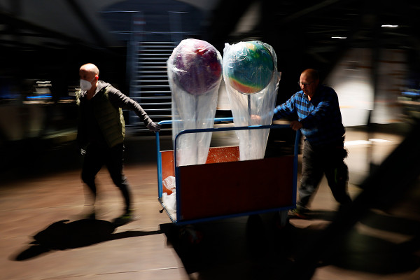 Zwei Globen werden durch zwei Mitarbeiter zu ihrem Bestimmungsort gebracht