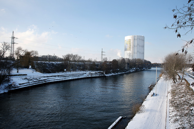 Verschneite Landschaftsaufnahme mit Gasometer im Hintergrund